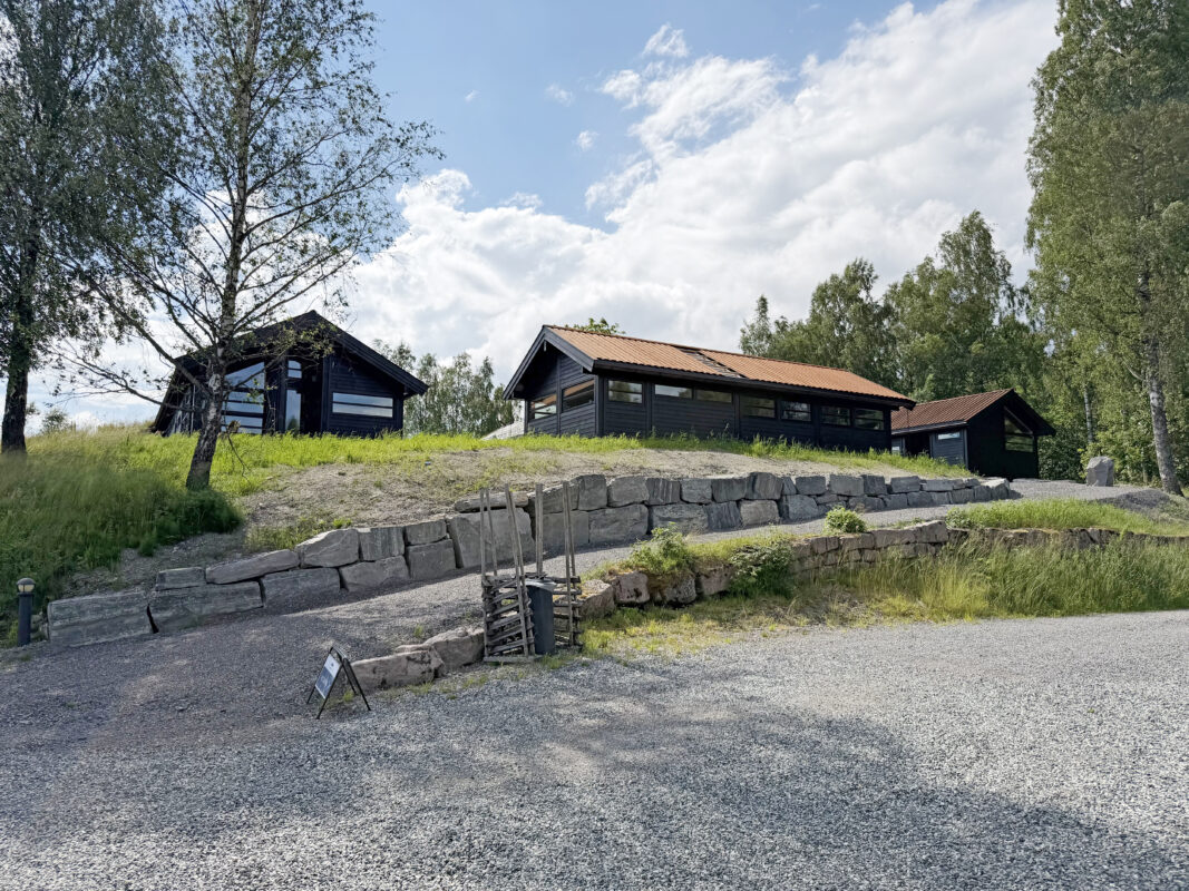 To Ål-hytter og et anneks, sett nedenfra med vei opp